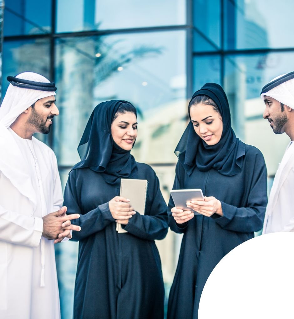Group of Emirati business professionals discussing documents outside a modern office building, representing collaboration and business setup in UAE.
