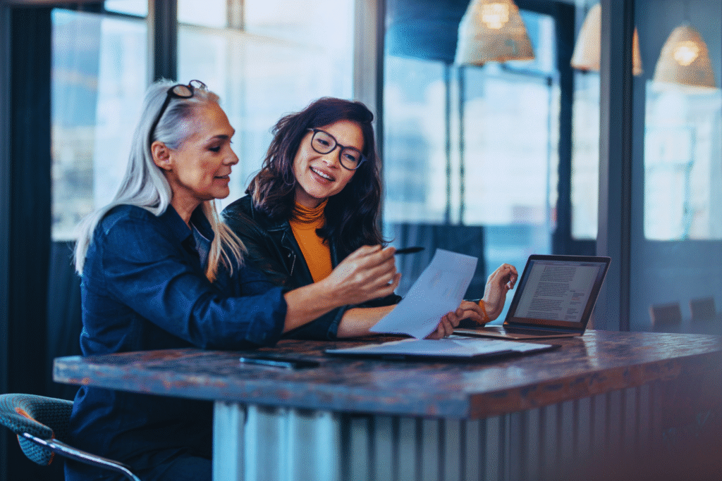 Two business professionals discussing documents for License & Visa services in a modern office, ensuring efficient approval and smooth processing in the UAE.