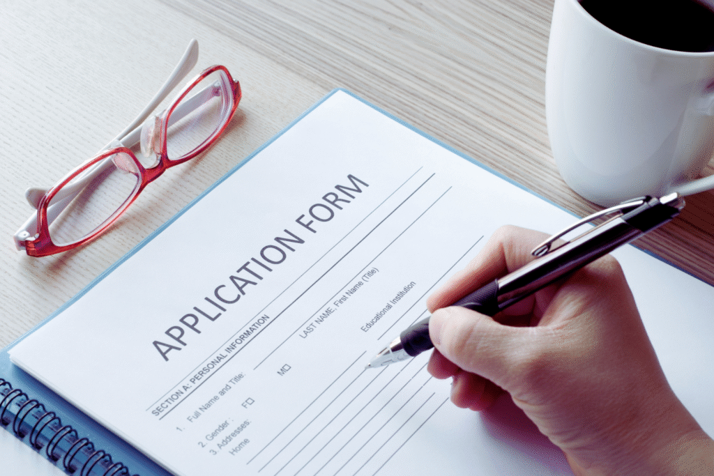 Person filling out an application form for SIRA Approval with pen and documents on desk